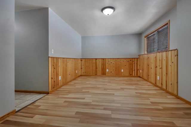 additional living space with wood walls and light hardwood / wood-style flooring