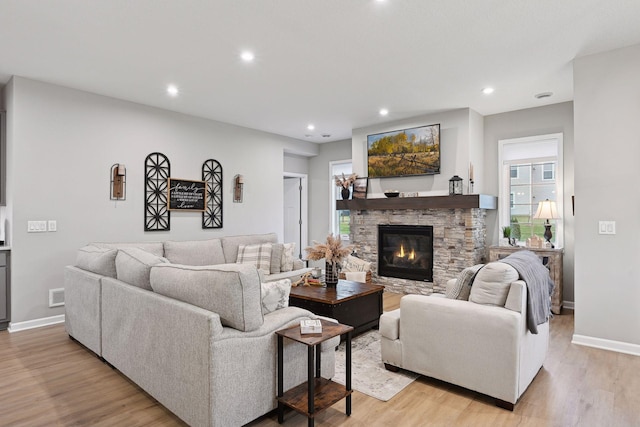 living room featuring a stone fireplace and light hardwood / wood-style flooring