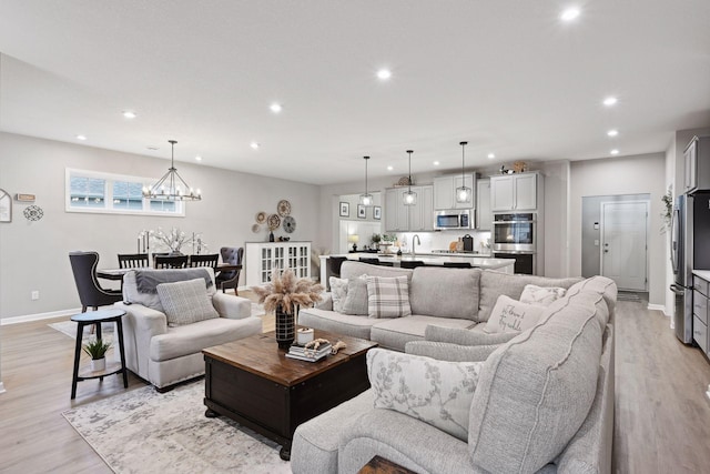 living room with a notable chandelier, light wood-type flooring, and sink