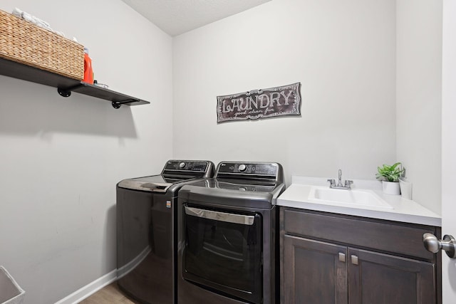 laundry room with cabinets, sink, hardwood / wood-style flooring, washing machine and dryer, and a textured ceiling