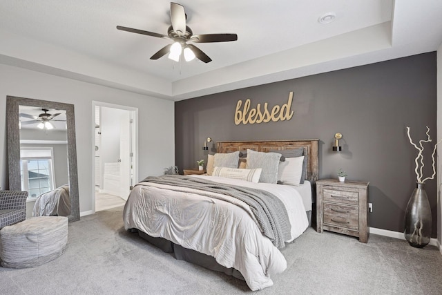 bedroom featuring carpet, ceiling fan, connected bathroom, and a tray ceiling