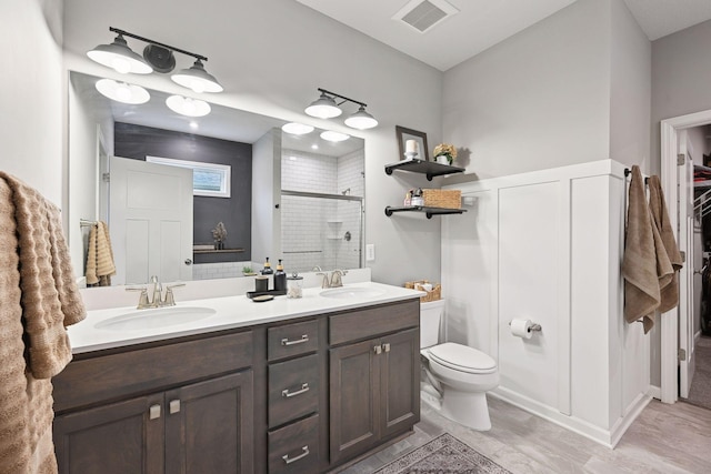 bathroom with hardwood / wood-style floors, vanity, toilet, and a shower with door