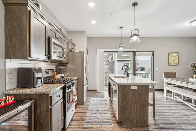 kitchen with sink, beverage cooler, backsplash, an island with sink, and appliances with stainless steel finishes