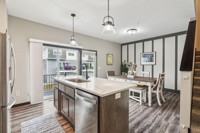 kitchen featuring dark brown cabinetry, sink, hanging light fixtures, a center island with sink, and appliances with stainless steel finishes