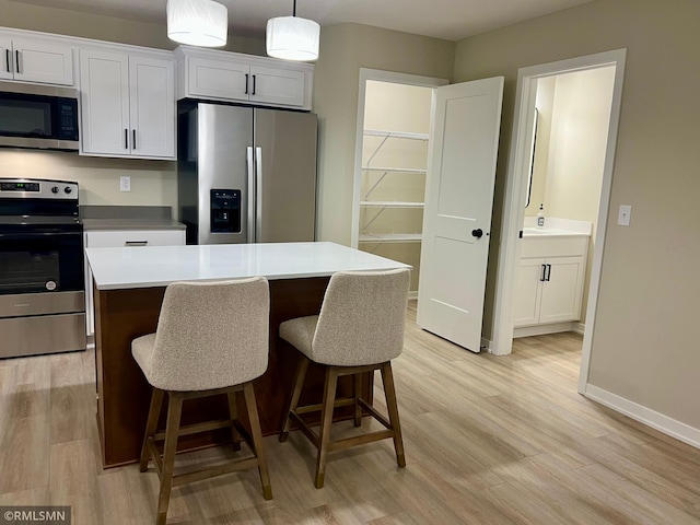 805 Tomahawk Ct, Madison Lake, MN 56063 - kitchen featuring a kitchen island, light wood-type flooring, a kitchen breakfast bar, and stainless steel appliances