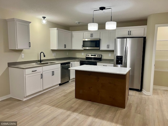 805 Tomahawk Ct, Madison Lake, MN 56063 - kitchen with white cabinets, appliances with stainless steel finishes, a sink, light wood-type flooring, and a center island