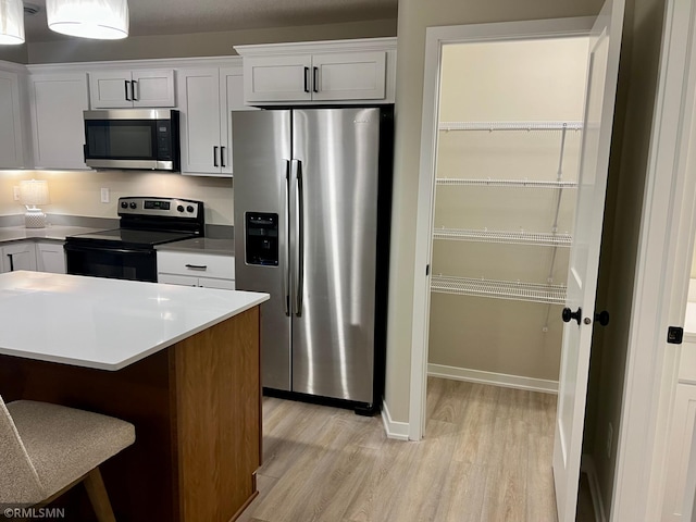 805 Tomahawk Ct, Madison Lake, MN 56063 - kitchen featuring a breakfast bar, appliances with stainless steel finishes, light wood-style flooring, baseboards, and white cabinets