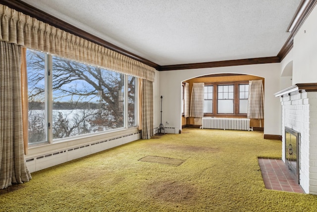 unfurnished living room featuring radiator, carpet, a baseboard heating unit, a brick fireplace, and a textured ceiling