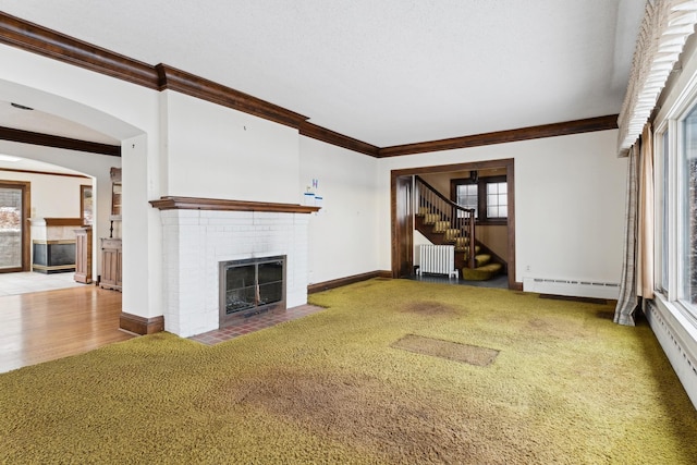 unfurnished living room featuring radiator, crown molding, carpet, a fireplace, and a baseboard radiator