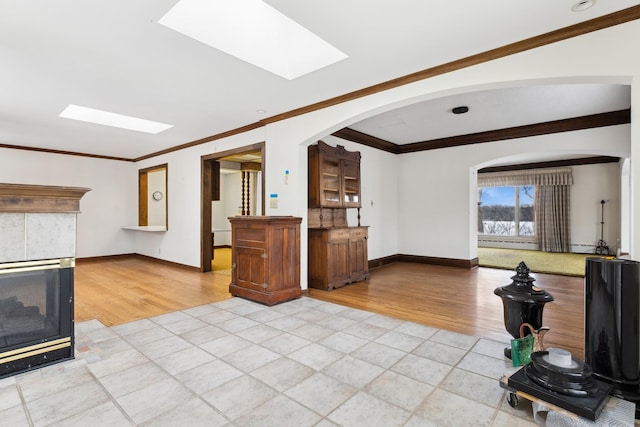 living room featuring crown molding, a skylight, and light hardwood / wood-style floors