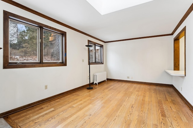 unfurnished room with a skylight, ornamental molding, radiator heating unit, and light hardwood / wood-style flooring