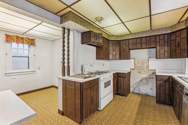 kitchen with a paneled ceiling, white gas range oven, and dark brown cabinets