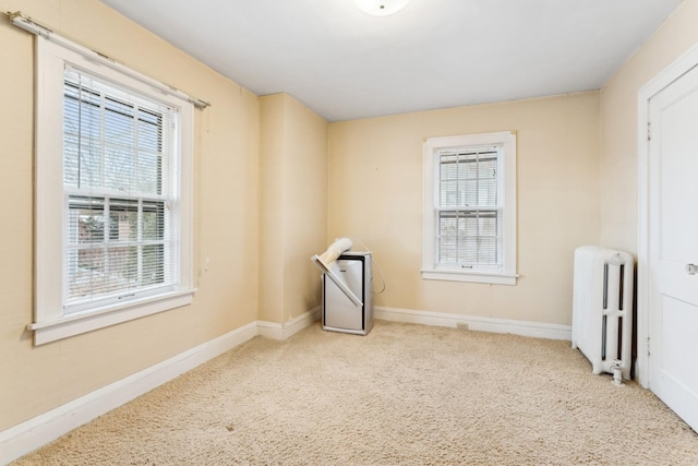 carpeted spare room featuring radiator and a wealth of natural light