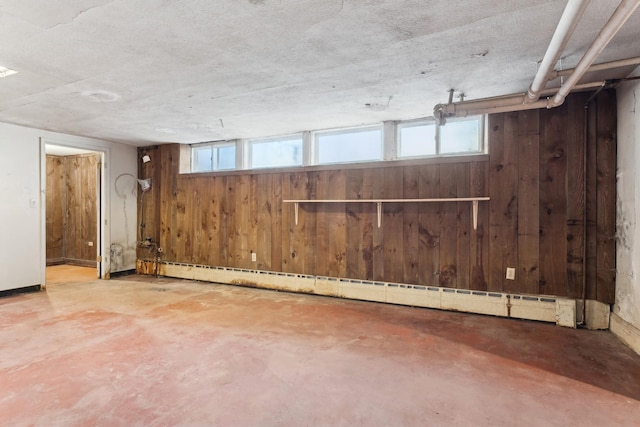 basement featuring a baseboard radiator and wooden walls