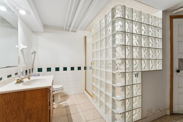 bathroom featuring tile walls, vanity, a shower, tile patterned floors, and toilet