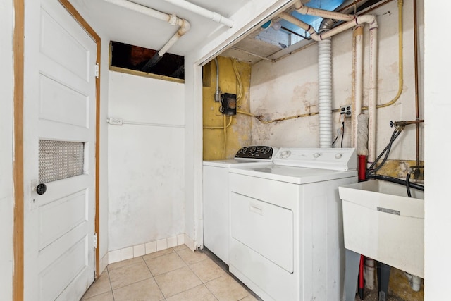 clothes washing area with sink, light tile patterned floors, and independent washer and dryer