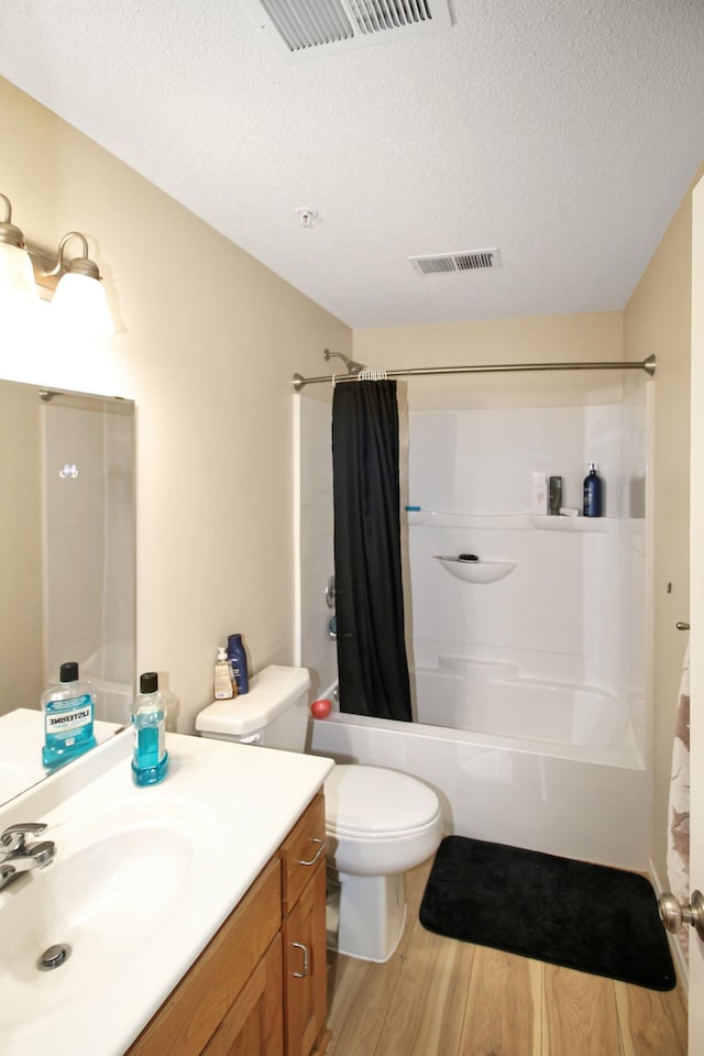 full bathroom with shower / bath combo, a textured ceiling, toilet, vanity, and hardwood / wood-style flooring