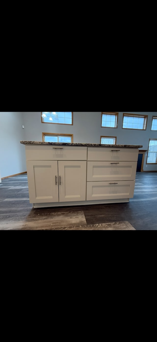 kitchen with dark stone countertops, white cabinetry, dark hardwood / wood-style flooring, and a healthy amount of sunlight