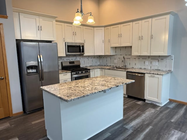 kitchen with tasteful backsplash, stainless steel appliances, sink, decorative light fixtures, and white cabinetry