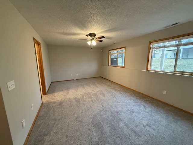 carpeted spare room featuring ceiling fan and a textured ceiling