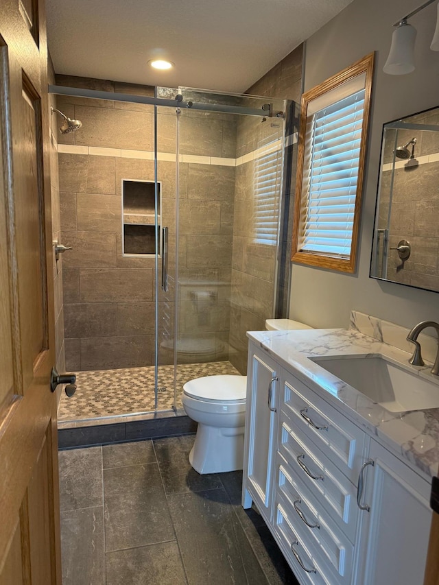 bathroom featuring tile patterned floors, vanity, an enclosed shower, and toilet