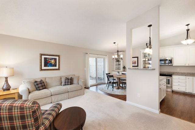 living room featuring dark wood-type flooring, lofted ceiling, and a notable chandelier