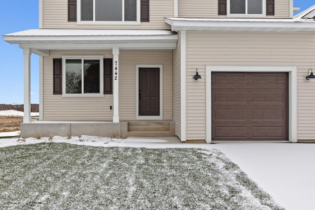 snow covered property entrance featuring a garage