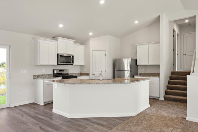 kitchen featuring a center island with sink, white cabinets, appliances with stainless steel finishes, and vaulted ceiling