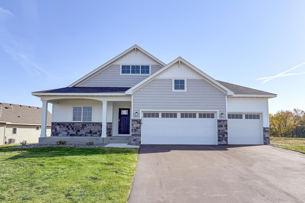 craftsman house featuring covered porch, a garage, a front lawn, and central air condition unit