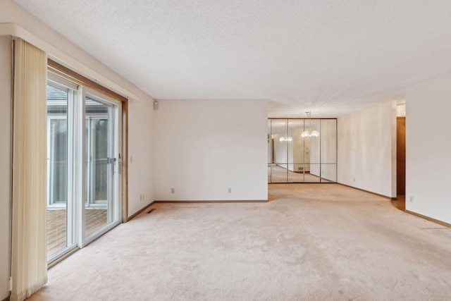 carpeted spare room featuring a chandelier and a textured ceiling