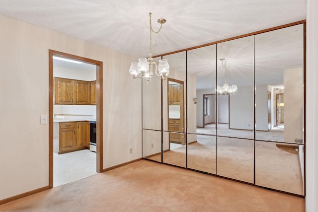 unfurnished bedroom featuring light carpet, a closet, a textured ceiling, and an inviting chandelier