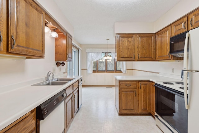 kitchen featuring pendant lighting, white appliances, sink, a textured ceiling, and a chandelier