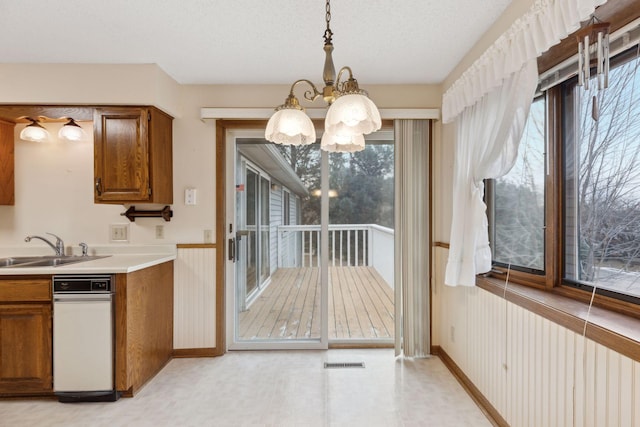 kitchen featuring a textured ceiling, decorative light fixtures, sink, and a chandelier