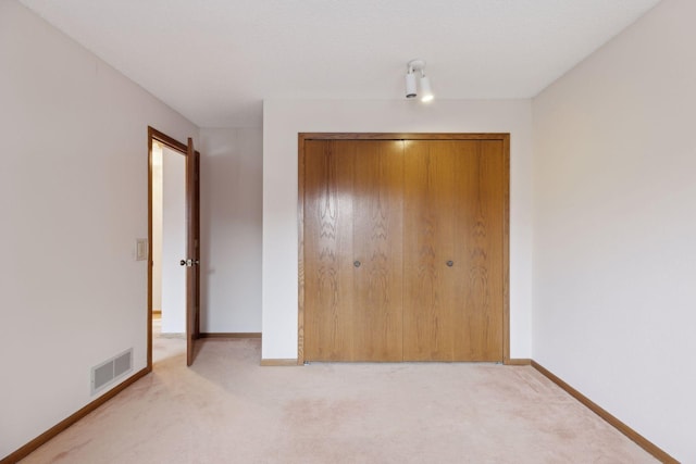 unfurnished bedroom with light carpet and a closet