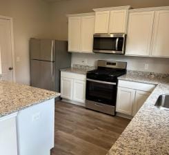 kitchen with light stone counters, dark hardwood / wood-style flooring, white cabinetry, and stainless steel appliances