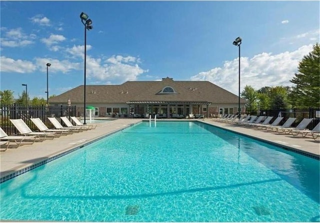 pool with a patio area and fence