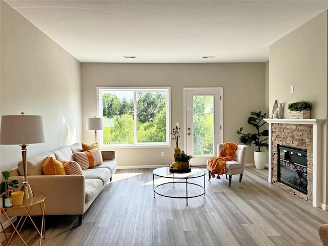 living room featuring a stone fireplace and light hardwood / wood-style floors