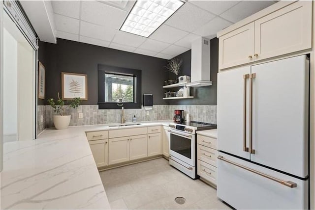 kitchen featuring sink, white appliances, a drop ceiling, decorative backsplash, and wall chimney exhaust hood