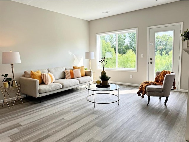 living room featuring visible vents, baseboards, and wood finished floors