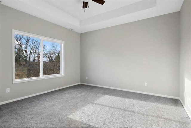 empty room featuring baseboards, a tray ceiling, ceiling fan, and carpet flooring