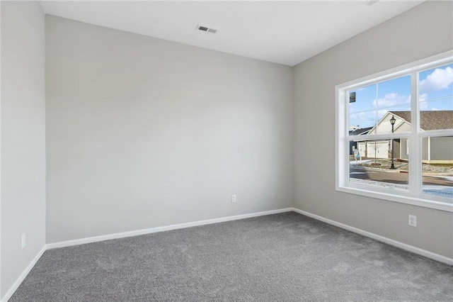 carpeted spare room with visible vents and baseboards