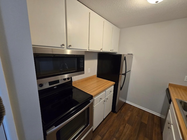 kitchen with white cabinets, appliances with stainless steel finishes, dark hardwood / wood-style flooring, and a textured ceiling