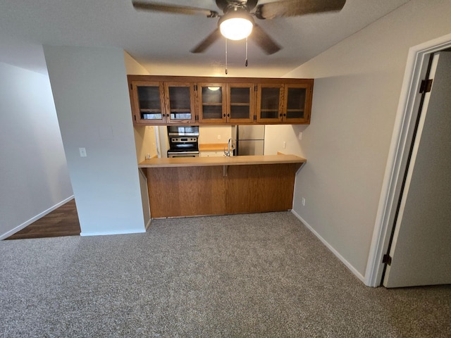 kitchen featuring kitchen peninsula, sink, dark colored carpet, and appliances with stainless steel finishes