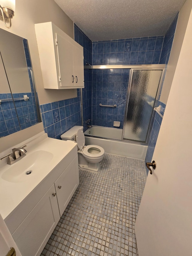 full bathroom featuring enclosed tub / shower combo, tile patterned floors, a textured ceiling, toilet, and tile walls