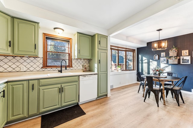 kitchen with dishwasher, sink, green cabinets, a chandelier, and decorative light fixtures