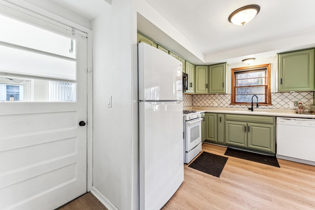 kitchen featuring white appliances, green cabinets, sink, light hardwood / wood-style flooring, and tasteful backsplash