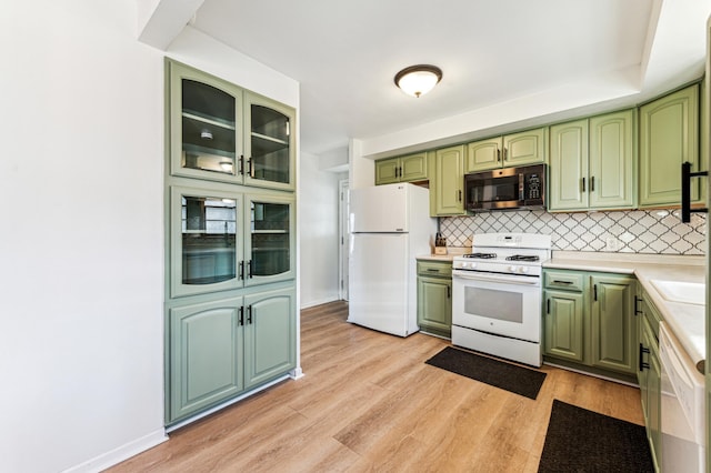 kitchen with tasteful backsplash, white appliances, light hardwood / wood-style flooring, and green cabinetry