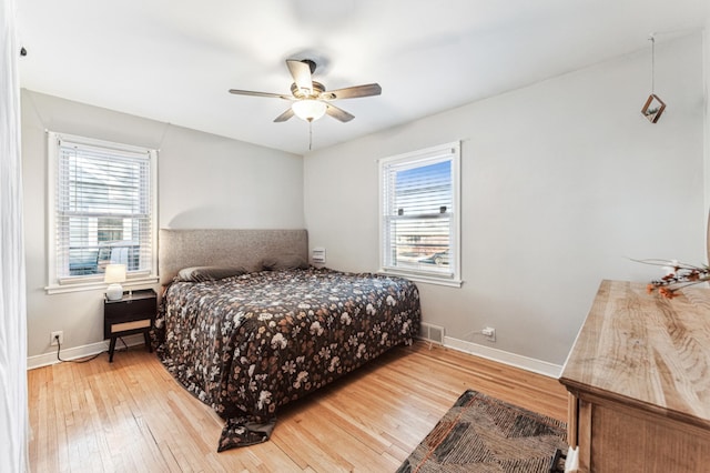 bedroom with hardwood / wood-style floors, ceiling fan, and multiple windows