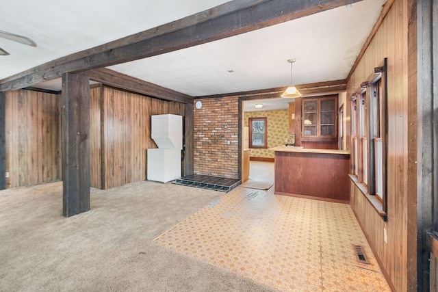 kitchen with decorative light fixtures, light carpet, and wooden walls