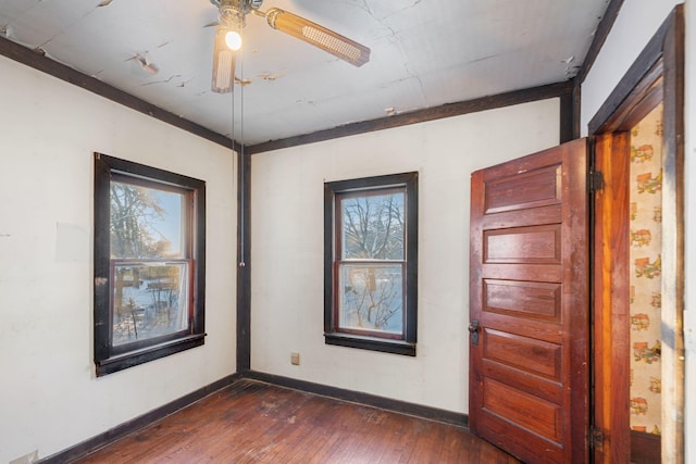 spare room with ceiling fan, a healthy amount of sunlight, and dark wood-type flooring